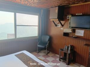 a bedroom with a bed and a television and a chair at New Malook hotel in Shimla