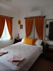 a bedroom with a large bed with orange curtains at Yükser Pansiyon in Side