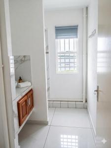 a white bathroom with a sink and a window at Location meublee Kourou pour 5 personnes plus 1 bebe in Kourou +25 photos