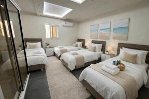 a bedroom with three beds with white sheets at The Perfect in Alexandria