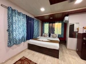a bedroom with a large bed with blue curtains at Crescent Holiday Homes in Panchgani