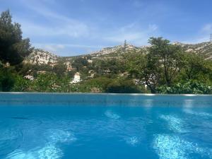 a blue swimming pool with mountains in the background at La Panouse in Marseille