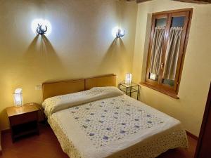 a bedroom with a bed and two lights on the wall at Nido in Toscana - Appartamento in Centro Storico con Aria Condizionata in Buonconvento