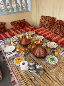 a table with plates of food on top of a couch at Waveside surf house in Tamraght Ou Fella