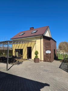 a large yellow building with a roof and a patio at Cosy Hideaway Guest House in Dovilai