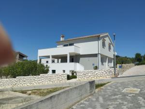 a white house with a stone wall next to a road at Apartman Goga i Dragan in Drage