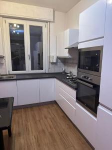 a kitchen with white cabinets and black appliances at Easy Room Italy Central Station in Milan