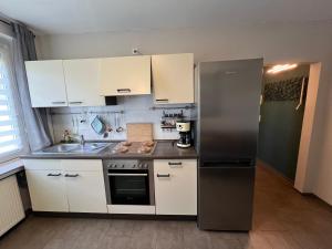 a kitchen with a stainless steel refrigerator and white cabinets at Über dem Dörpken in Wuppertal