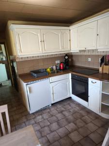 a kitchen with white cabinets and a stove top oven at Ferienhaus König in Kurort Steinbach-Hallenberg +3 photos