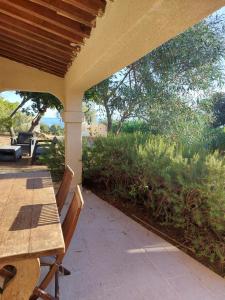 a porch with a wooden table and chairs and a field at villa des calanques in Conca