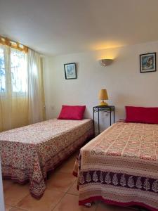 a hotel room with two beds with red pillows at villa des calanques in Conca