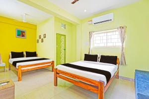 two beds in a room with yellow walls at Hotel O by OYO LA VGA RESIDENCY in Kottakupam