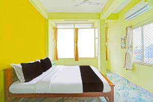 a bedroom with a bed with yellow walls and windows at Hotel O by OYO LA VGA RESIDENCY in Kottakupam