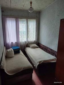 two beds in a small room with a window at Ksenia pansionat in Skhidnitsa