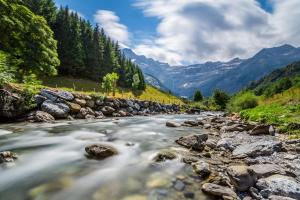 a river with rocks and mountains in the background at Le Petit Jaune in Orthez