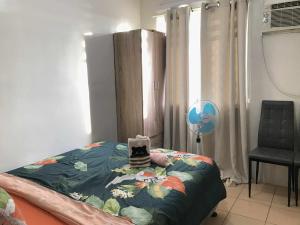 a bedroom with a bed and a chair and a window at MJ Luxury Living in Iloilo City