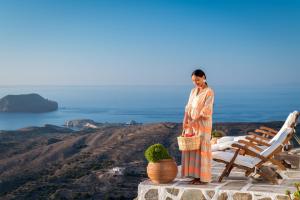 a woman standing on a ledge overlooking the ocean at Castrum Traditional Sunset Suites in Plaka Milou