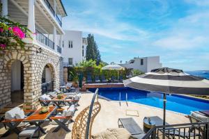 a patio with a table and an umbrella next to a pool at Noa Suite Hotel Only Adult in Bodrum City