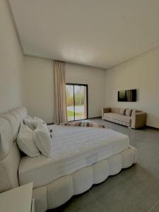 a large white bed in a room with a couch at Villa Dream el filali in Sraghna