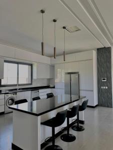 a large kitchen with a black counter and black chairs at Villa Dream el filali in Sraghna