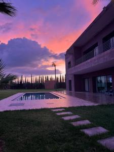 a sunset over a house with a swimming pool at Villa Dream el filali in Sraghna