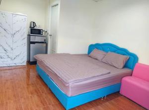 a bed with a blue headboard and a pink couch at Nopphadon Hotel in Lat Krabang