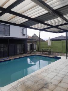 a swimming pool with a pergola and a picnic table at The Seige Guesthouse in Pretoria