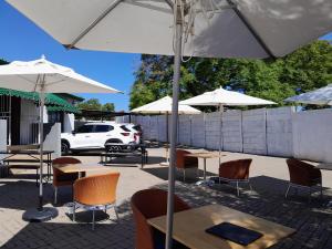 a patio with tables and chairs and umbrellas at The Seige Guesthouse in Pretoria