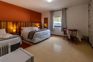 un dormitorio con dos camas y una mesa y un escritorio en Hotel Ascona, en Campos do Jordão