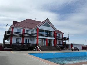 a red and white house with a pool in front of it at Готель-ресторан Октан in Holovanivs'k