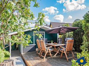 a deck with a table and chairs and an umbrella at Fraeulein Loddin Whg_ Hugo in Kölpinsee