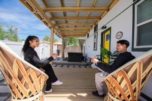 people sitting on the porch of a house at The Frida Tiny House-Hot Tub-Pet Friendly-No Pet Fee! in Albuquerque