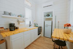 a kitchen with white cabinets and a table and a refrigerator at The Frida Tiny House-Hot Tub-Pet Friendly-No Pet Fee! in Albuquerque