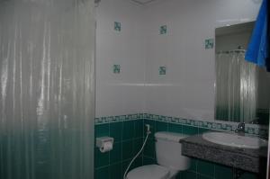 a green bathroom with a toilet and a sink at Baan Manthana House in Hua Hin