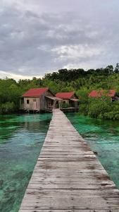 a wooden bridge over a body of water with houses at Raja Ampat Blue Sea in Besir +73 photos