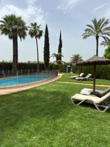 a lawn with chairs and an umbrella and a swimming pool at La Casa de los Limones in Montilla