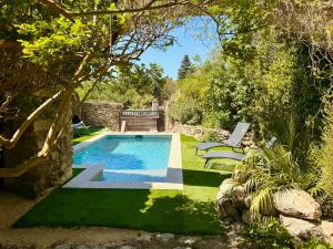 a swimming pool in a garden with two lawn chairs at Le jardin de Grignan in Réauville