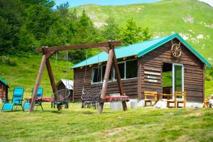 a log cabin with a swing and a house at Eko Katun Kolijevka in Berane