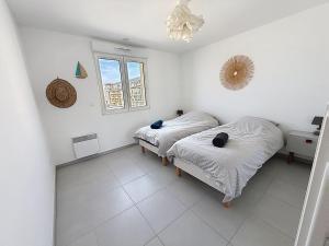 two beds in a white room with a window at Les Sables 4 in Fort-Mahon-Plage