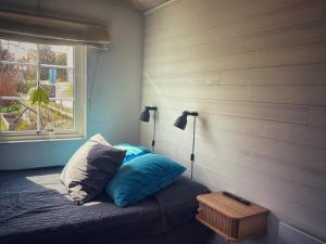 a bedroom with a bed with blue pillows and a window at Stuga smögen in Smögen