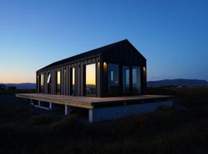 a small black house with windows on a field at Bárucottage in Eyrarbakki