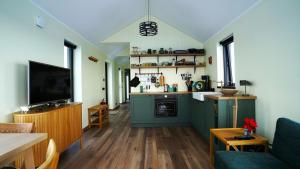 a kitchen with green cabinets and a living room at Bárucottage in Eyrarbakki