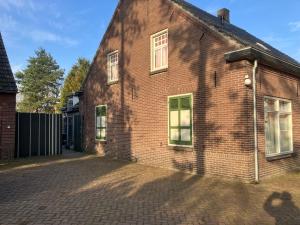 an old brick building with windows on a brick driveway at Het werkhuis, terug in de tijd in Uden