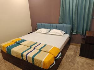 a bedroom with a bed with a striped blanket on it at PVR Grand Residency in Tiruvannāmalai +8 photos