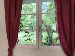 a window with red curtains looking out at a tree at Aubrion de Cremens in Magnan