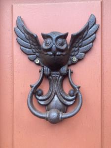 a metal owl decoration on a red door at La Maison de Traverse in Vichy
