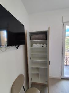 ein Zimmer mit einem Fernseher und einem Schrank mit Regalen in der Unterkunft Nbm in Puerto de Gandía + 11 Fotos