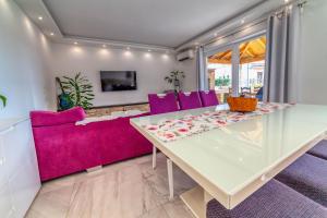 a dining room with a glass table and purple chairs at Bella Casa in Sukošan