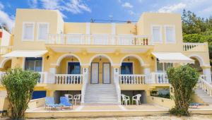 a yellow house with a balcony and chairs at Pantelis Studio in Paralia Agias Foteinis