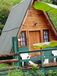 a log cabin with two chairs and an umbrella at Chalés FRONT LAKE 2 in Córrego do Bom Jesus